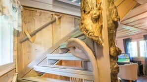 A wooden staircase with a unique design, a rustic tree trunk sculpture, and a modern room with a television. - Runopuro by Interhome (Rautalampi)