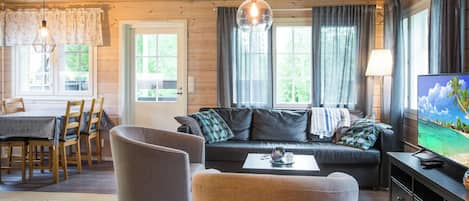 Ein gemütliches Wohnzimmer mit einer Couch, Sesseln, einem Couchtisch und einem Fernseher.