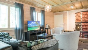 A cozy living room with a wooden ceiling, a television, a fireplace, and a comfortable seating area. - Runopuro by Interhome (Rautalampi)