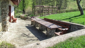 A stone building with a wooden roof, outdoor seating, and a grassy area with trees. - Vacation home Lhotka by Interhome (Ostravice)