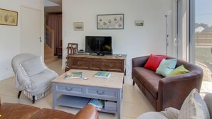 Ein Wohnzimmer mit Fernseher, einer Couch, einem Sessel und einem Couchtisch.