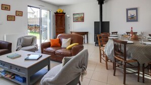 Ein Wohnzimmer mit einem braunen Ledersofa, einem grauen Sessel, einem Couchtisch und einem Essbereich mit Tisch für vier Personen.