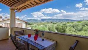 Un balcón con mesa y sillas, con vistas a un paisaje montañoso.