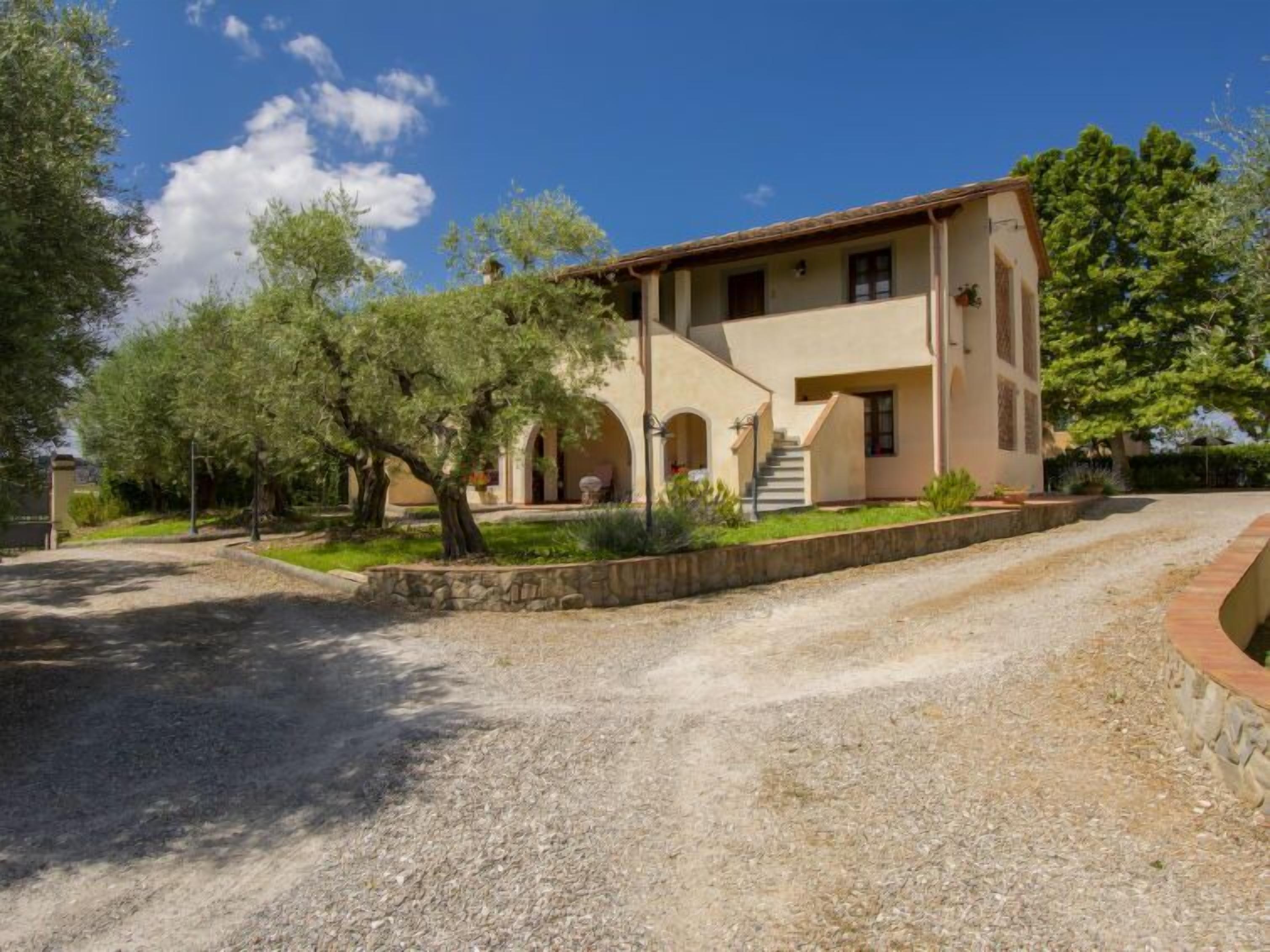 A two-story building with a stone facade, a central staircase, and a gravel driveway.