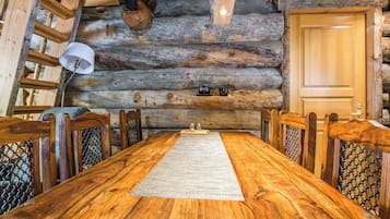 Un tavolo da pranzo in legno con sedie, un tappeto e una porta in legno in un interno di una baita.