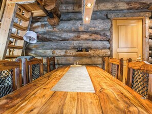 A wooden dining table with chairs, a rug, and a wooden door in a log cabin interior. - Seitsemän savua 4 by Interhome (Kuusamo)