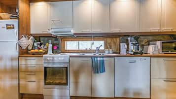 Una cucina con piano cottura, forno, lavastoviglie e una finestra sopra il lavello.