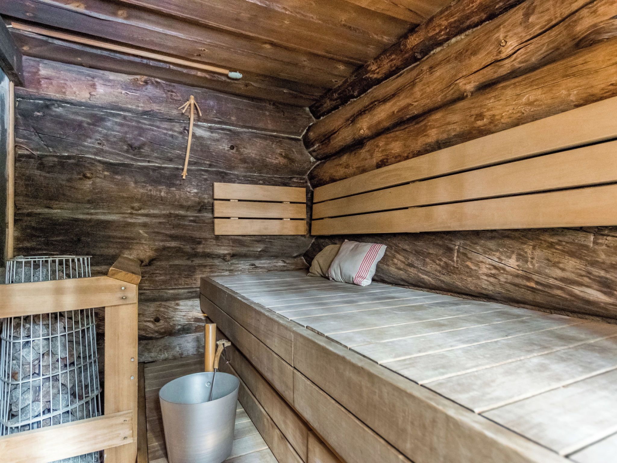 A wooden cabin with a bunk bed, a metal bucket, and a wooden ladder.