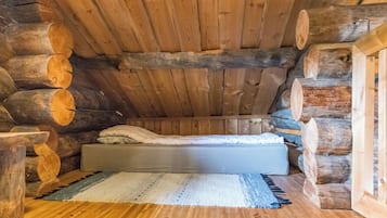 Camera da rifugio in legno con un letto, un tappeto e tronchi di legno a formare le pareti.