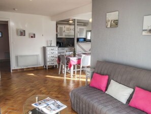 A cozy living room with a grey sofa and a dining area with a table and chairs. - Les Embruns by Interhome (Carnac)