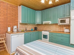 A kitchen with teal cabinets, a microwave, a stove, and a dishwasher. - Laavusranta by Interhome (Mikkeli)