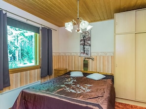 Quarto com cama, janela com cortinas, lustre e guarda-roupa.
