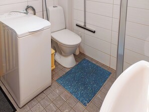 Ein Badezimmer mit Toilette, Waschmaschine, Dusche und einer blauen Matte.