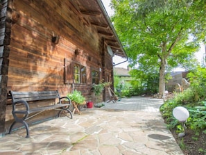 A rustic wooden building with a stone-paved entrance, a bench, and potted plants. - Waldner by Interhome (Telfs)