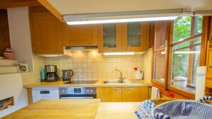 A compact kitchen with wooden cabinets, a stainless steel sink, and a window providing natural light.