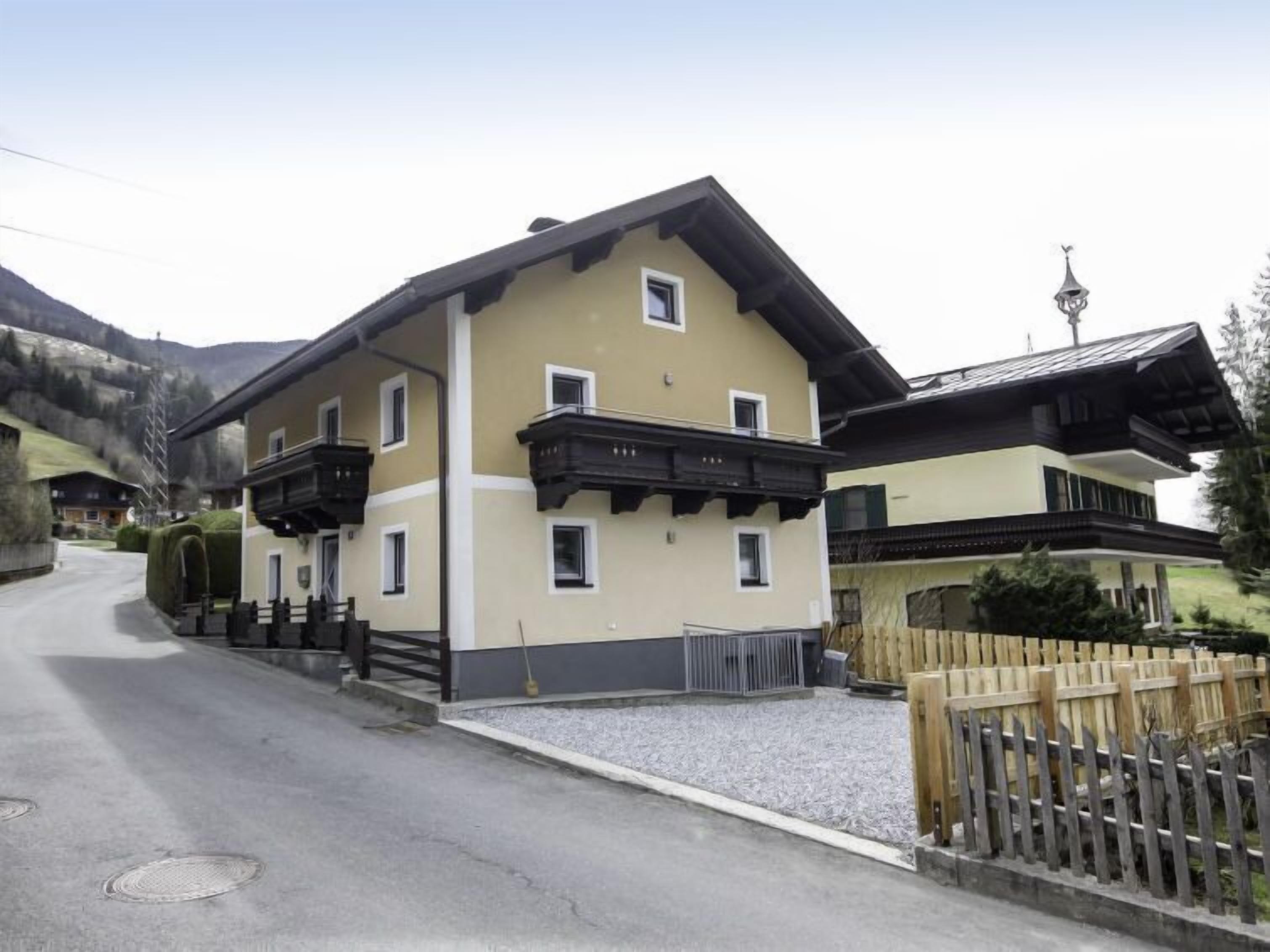 Un bâtiment à deux étages doté de balcons, d’une allée en gravier et d’une clôture en bois.