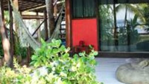 Una estructura de madera con un espacio de estar cubierto, una pared roja y un ventanal.