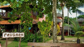 Resort tropical com uma placa indicando 'POUSADA', mostrando uma construção com telhado de palha.