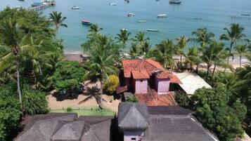 Uma vila costeira com casas tradicionais de telhado de palha, uma praia e um cais com barcos.