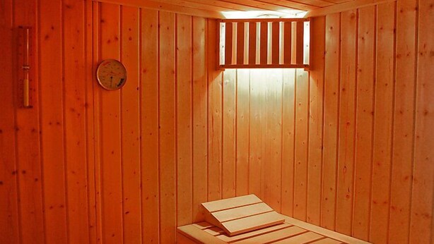 A sauna room with wooden walls and a bench.
