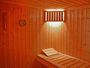 Un sauna avec des murs en bois et un banc.