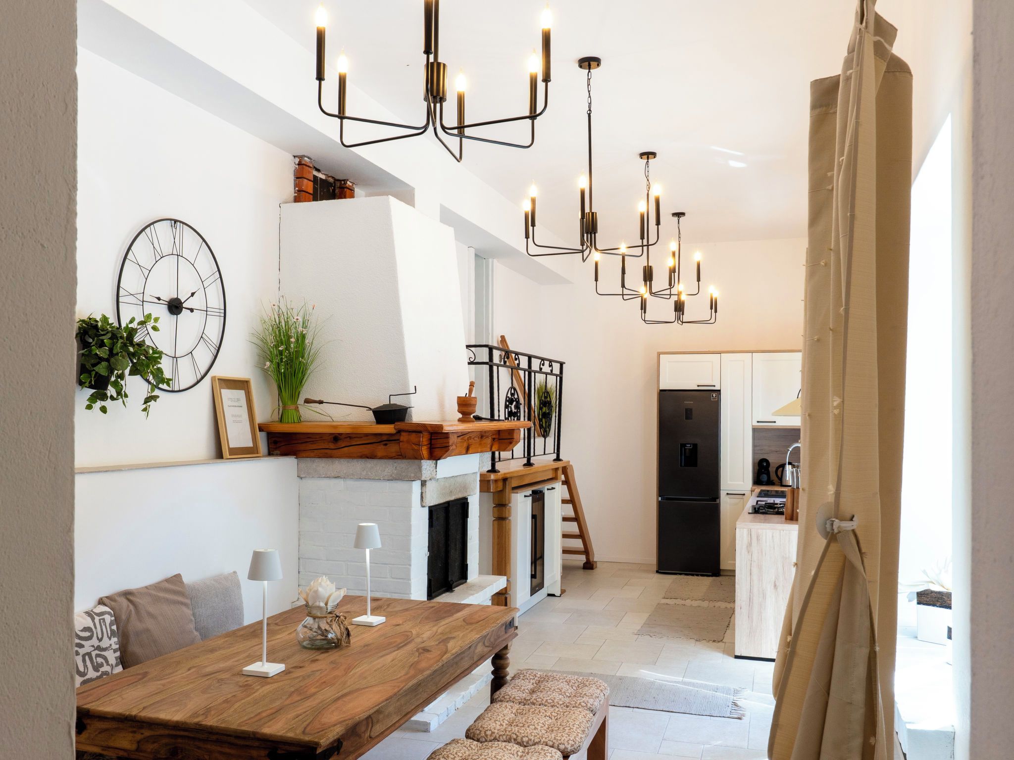 A modern kitchen with a central island, pendant lighting, and a dining area with a wooden table and bench.