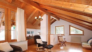 A cozy attic room with wooden beams, a dining table, a sofa, and a chair. - Seekarblick by Interhome (Achenkirch)