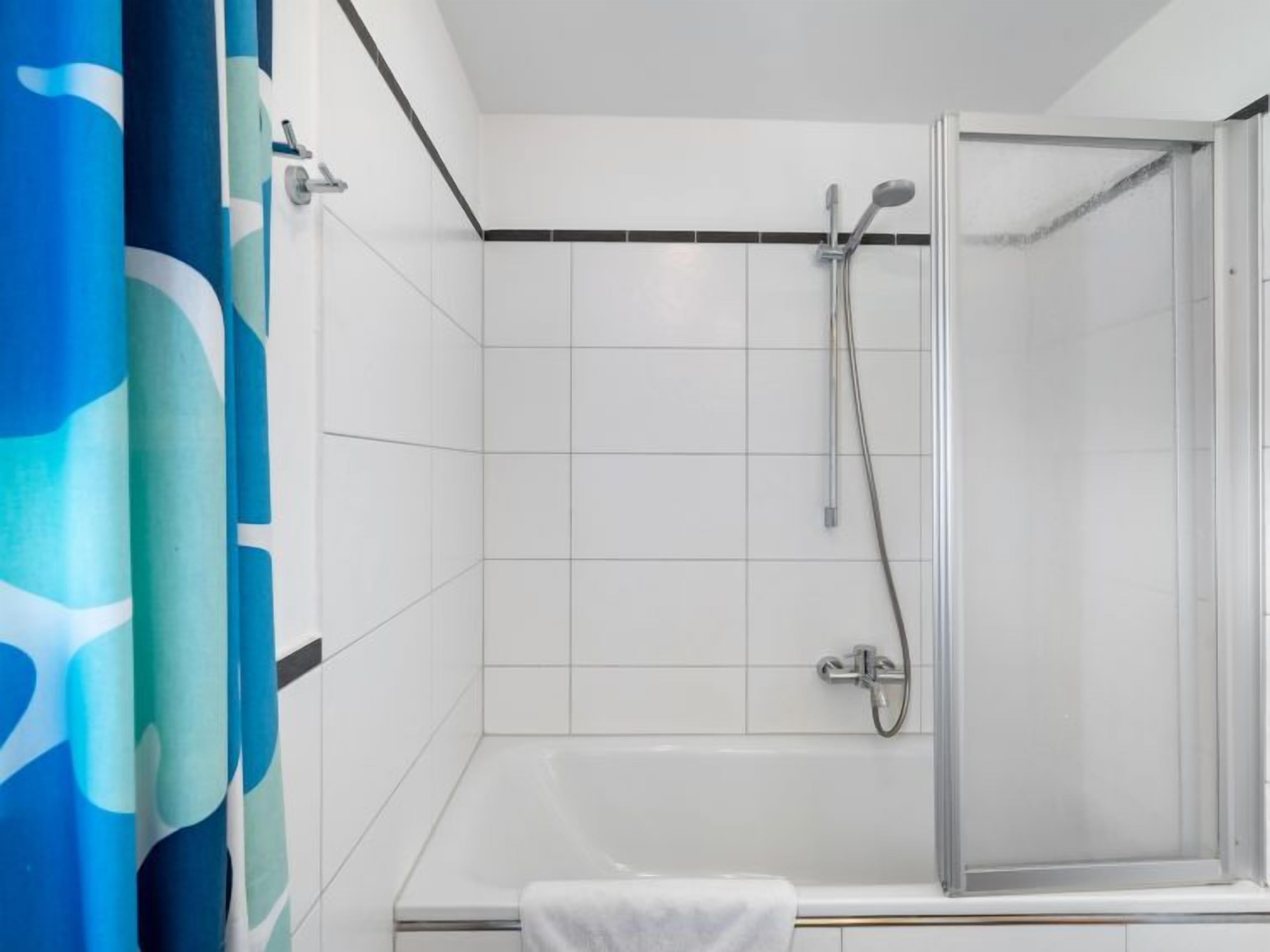A bathroom with a shower, a bathtub, and a curtain.