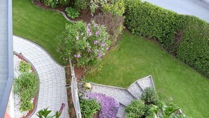 En anlagt have med en buet sti, forskellige buske og blomstrende planter.