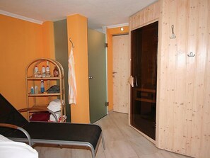 Ett rum med en säng, en garderob i trä, en hylla med toalettartiklar och en dörr som leder till ett annat rum.