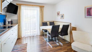 Et moderne hotelværelse med spiseplads, et fladskærms-tv, kaffemaskine og sofa.