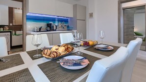 Une cuisine moderne avec un revêtement mural bleu et un coin repas où une table est dressée pour quatre personnes.