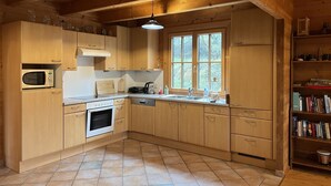 A wooden kitchen with a microwave, oven, and sink.