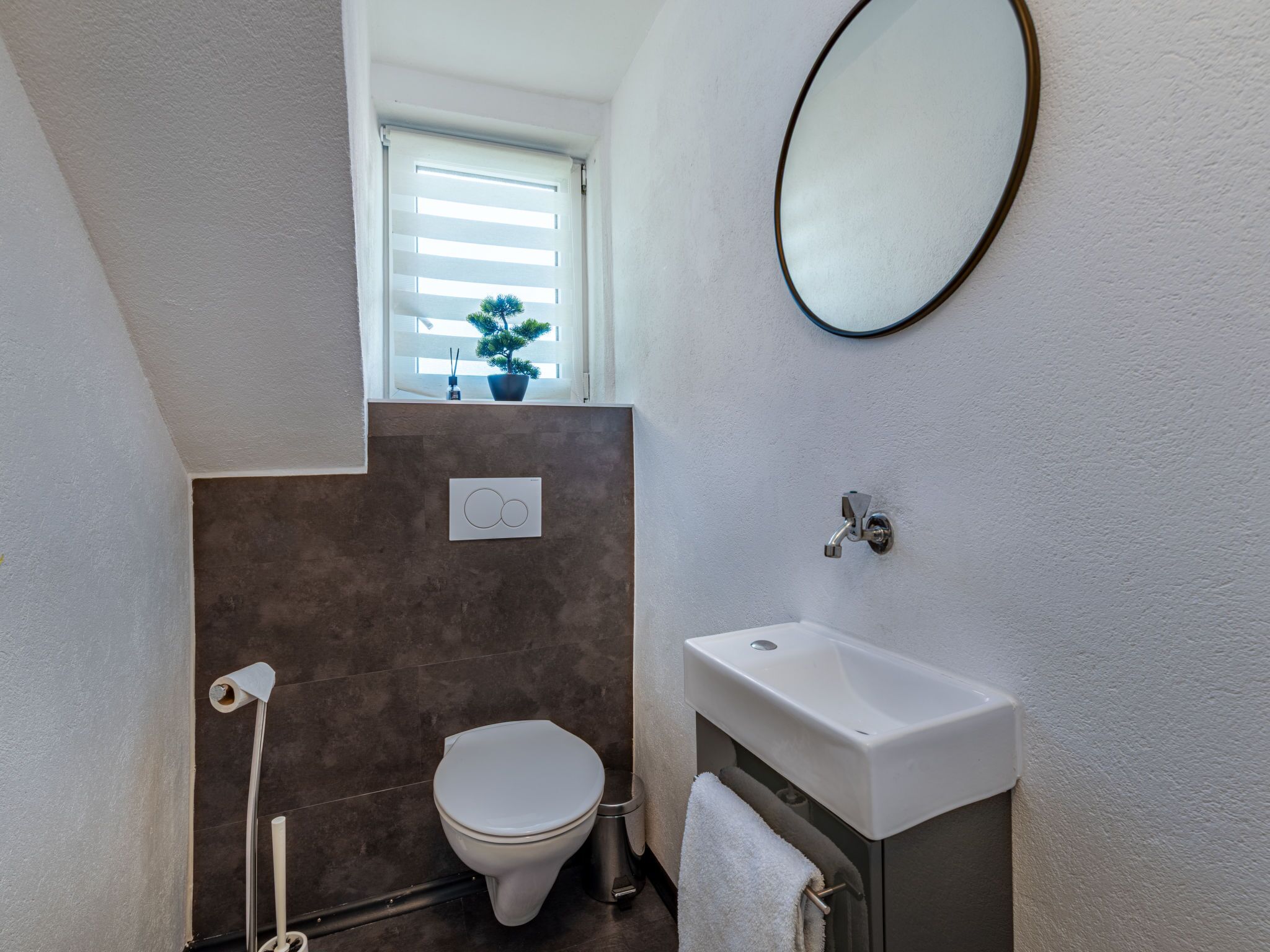A compact bathroom with a toilet, sink, and window.
