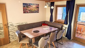 A dining area with a wooden table, grey upholstered chairs, a bench, and a painting of a landscape.