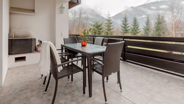 Ein Balkon mit Tisch, Stühlen, einem Grill und Blick auf die Berge.