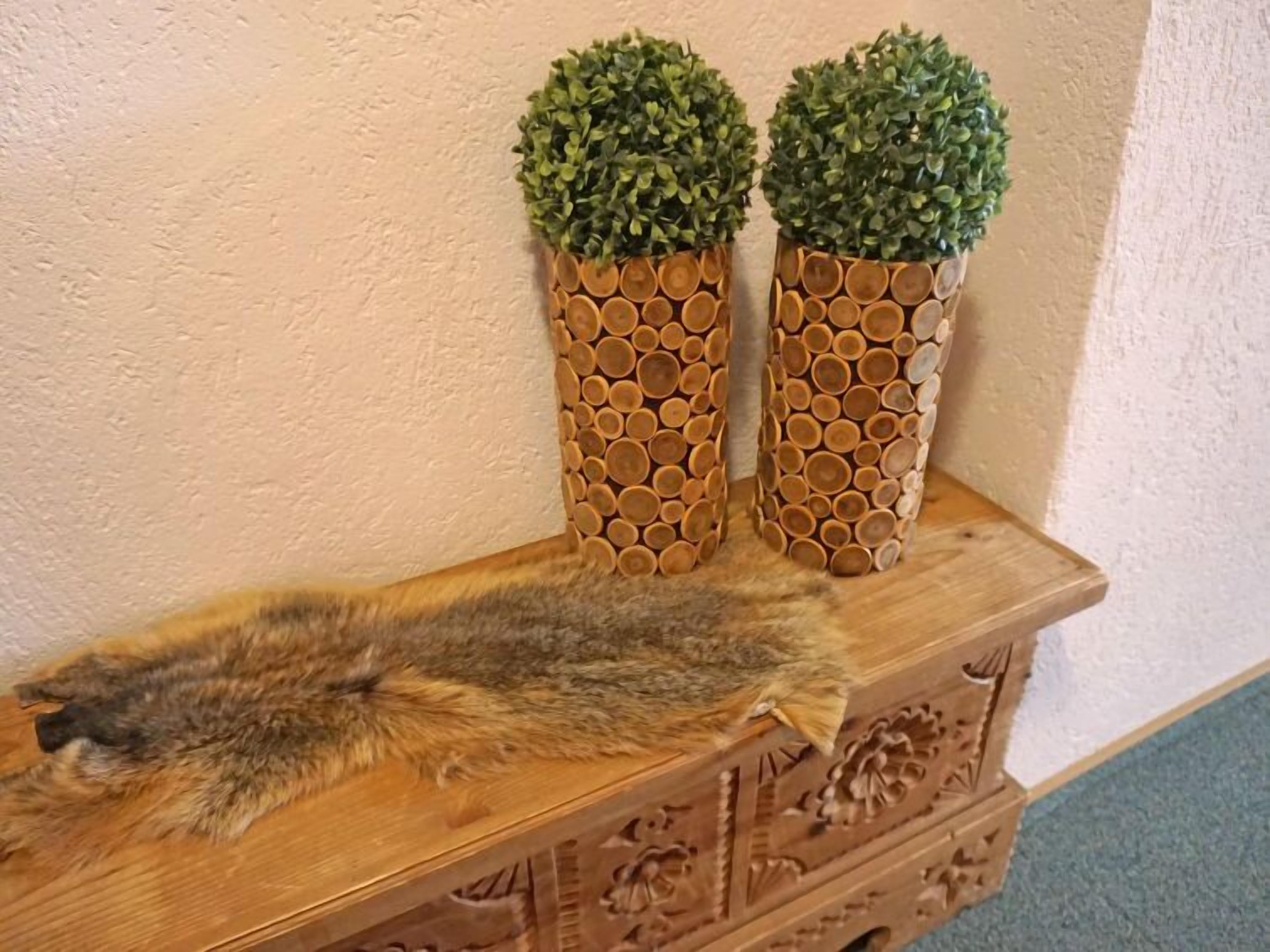 Un cofre de madera con intrincados grabados, dos jarrones cilíndricos con un diseño de panal y un gato acostado encima.