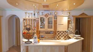 Une cuisine dotée d’un îlot central, de meubles de rangement en bois et d’une variété d’ustensiles de cuisine exposés sur des étagères.