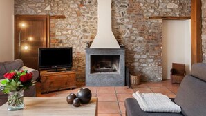 A cozy living room with a stone wall, a fireplace, a television, and a sofa. - La Bastide by Interhome (Thy-le-Bauduin)