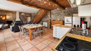 A rustic kitchen with a stone wall, wooden beams, and a tiled floor. - La Bastide by Interhome (Thy-le-Bauduin)