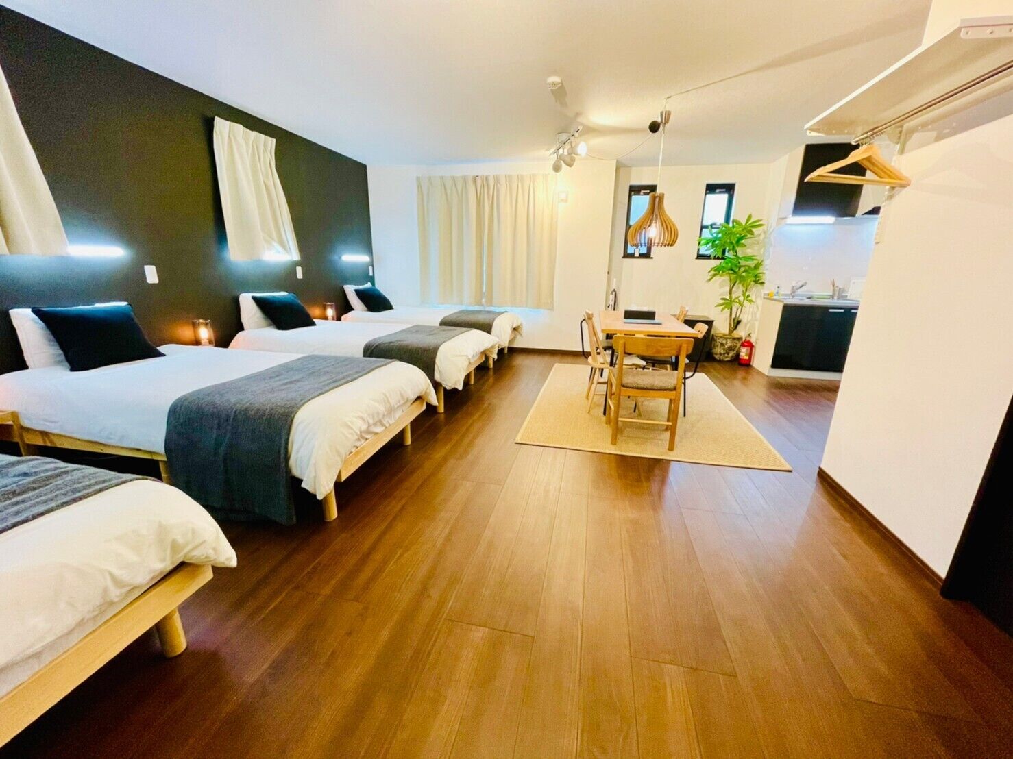 Een hotelkamer met drie bedden, een eettafel en een kitchenette.