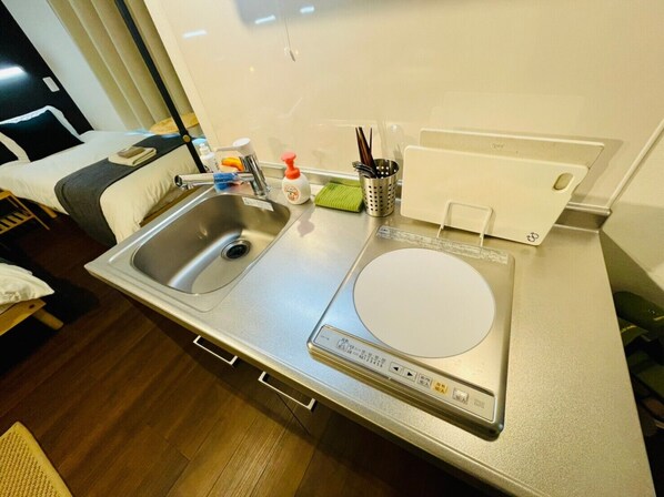 Een compacte keuken met een roestvrijstalen spoelbak, een ingebouwde rijstkoker en een klein aanrecht.