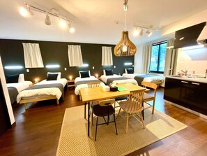A modern hotel room with four single beds, a wooden dining table, and a kitchen area. - Hotel Classy Skytree (Tokyo)