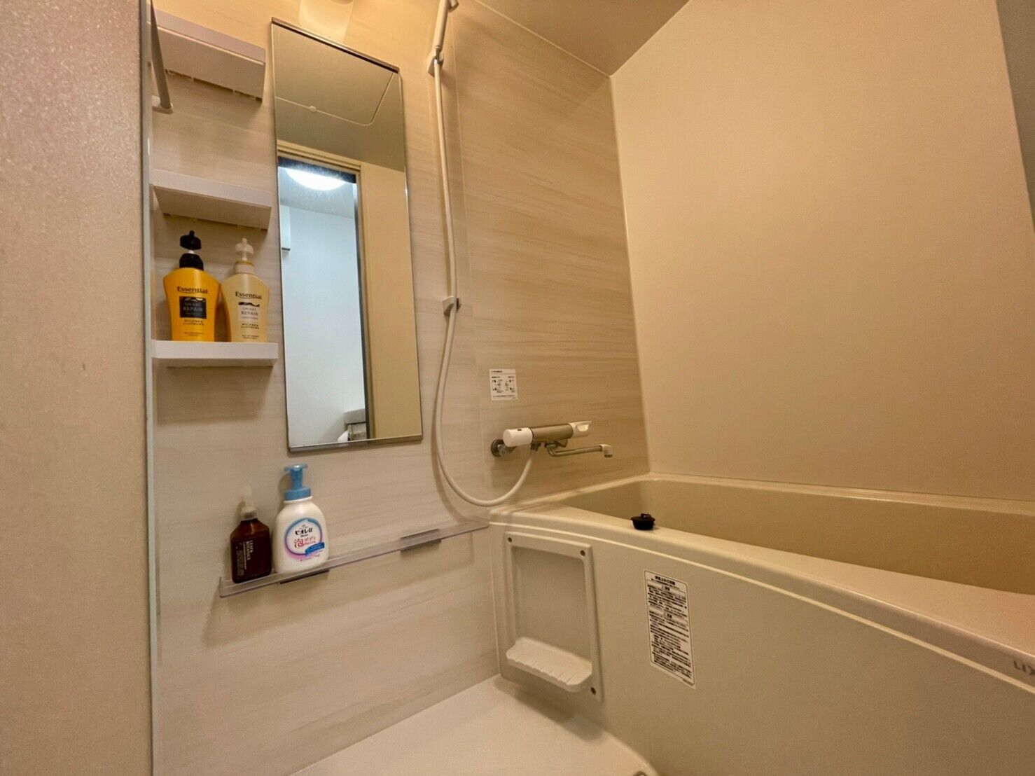 Ein kleines Badezimmer mit Badewanne, Spiegel und Ablagefläche für Toilettenartikel.