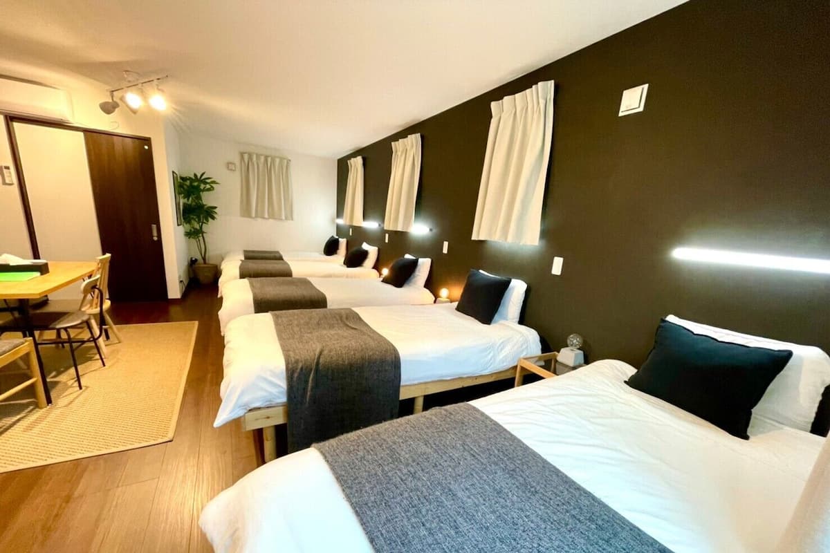 A hotel room with three beds, a desk, and a chair.