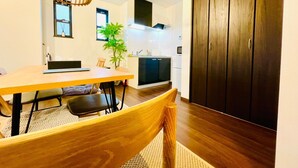 Een moderne keuken met een eethoek, bestaande uit een houten tafel, stoelen en een hangende lamp.