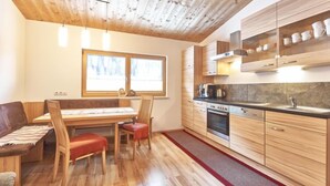 Una cocina moderna con armarios de madera, un comedor con mesa y sillas de madera, y un ventanal que proporciona luz natural.