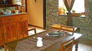 A dining area with a wooden table, chairs, and a stone wall. - Ma Campagne by Interhome (Trois-Ponts)
