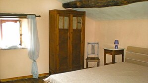 A bedroom with a wooden bed, a wooden wardrobe, a chair, a small table with a lamp, and a window with a curtain. - Ma Campagne by Interhome (Trois-Ponts)
