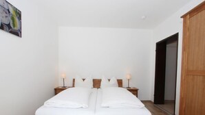 A bedroom with a wooden bed, two bedside tables with lamps, and a wooden wardrobe. - Apartment Liebl by Interhome (Seefeld in Tirol)